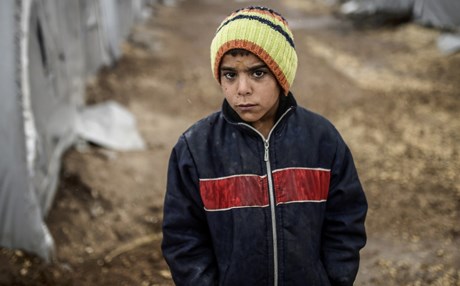 A Kurdish refugee boy stands during a rainy day at the Rojova Camp, in Suruc, a rural district of Sanliurfa Province, on October 30, 2014. Heavily armed Kurdish peshmerga fighters were on their way by land and by air, joining militias defending the Syrian border town of Kobane, also known as Ain al-Arab, from the Islamic State group after setting off from Iraq. Kobane's Kurdish defenders have been eagerly waiting for the peshmerga since Turkey last week said it would allow them to traverse its territory to enter the town. AFP PHOTO/ BULENT KILIC (Photo credit should read BULENT KILIC/AFP/Getty Images)